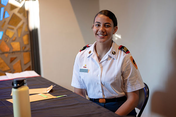 A smiling student sitting at a desk in uniform